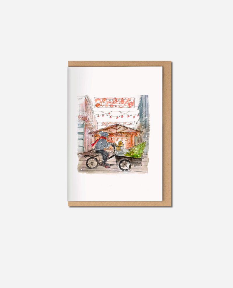 Watercolour Christmas card showing person on cargo bicycle with cockapoo riding through Manchester street decorated with red lanterns