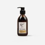 Amber glass pump bottle of Citrus Vulgaris hand wash with black dispenser and cream label featuring bird illustration by The Sculpts