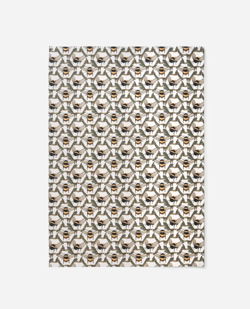 Honeycomb Bee tea towel by The Sculpts displaying full repeating pattern with twin bees, green foliage, and golden honeycomb geometry on cream cotton