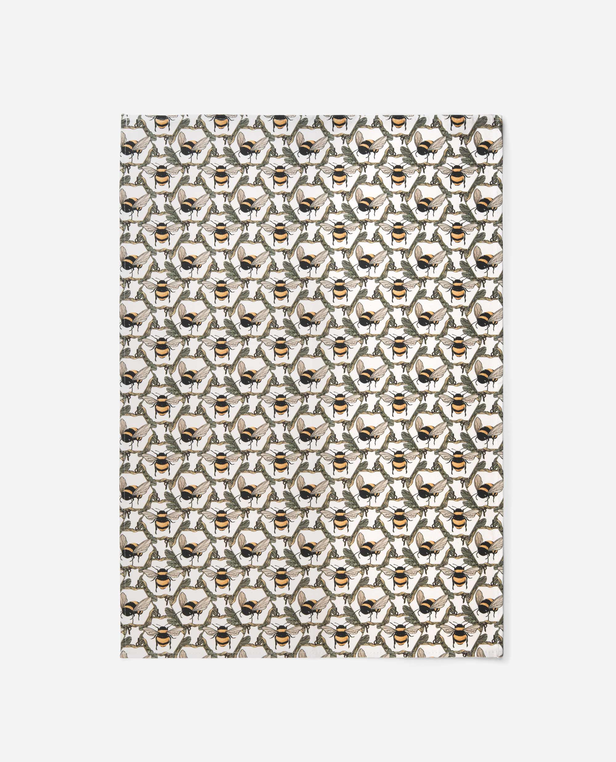 Honeycomb Bee tea towel by The Sculpts displaying full repeating pattern with twin bees, green foliage, and golden honeycomb geometry on cream cotton